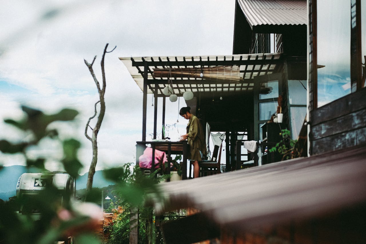 A woman working outdoors at a rustic wooden home with scenic mountain views.