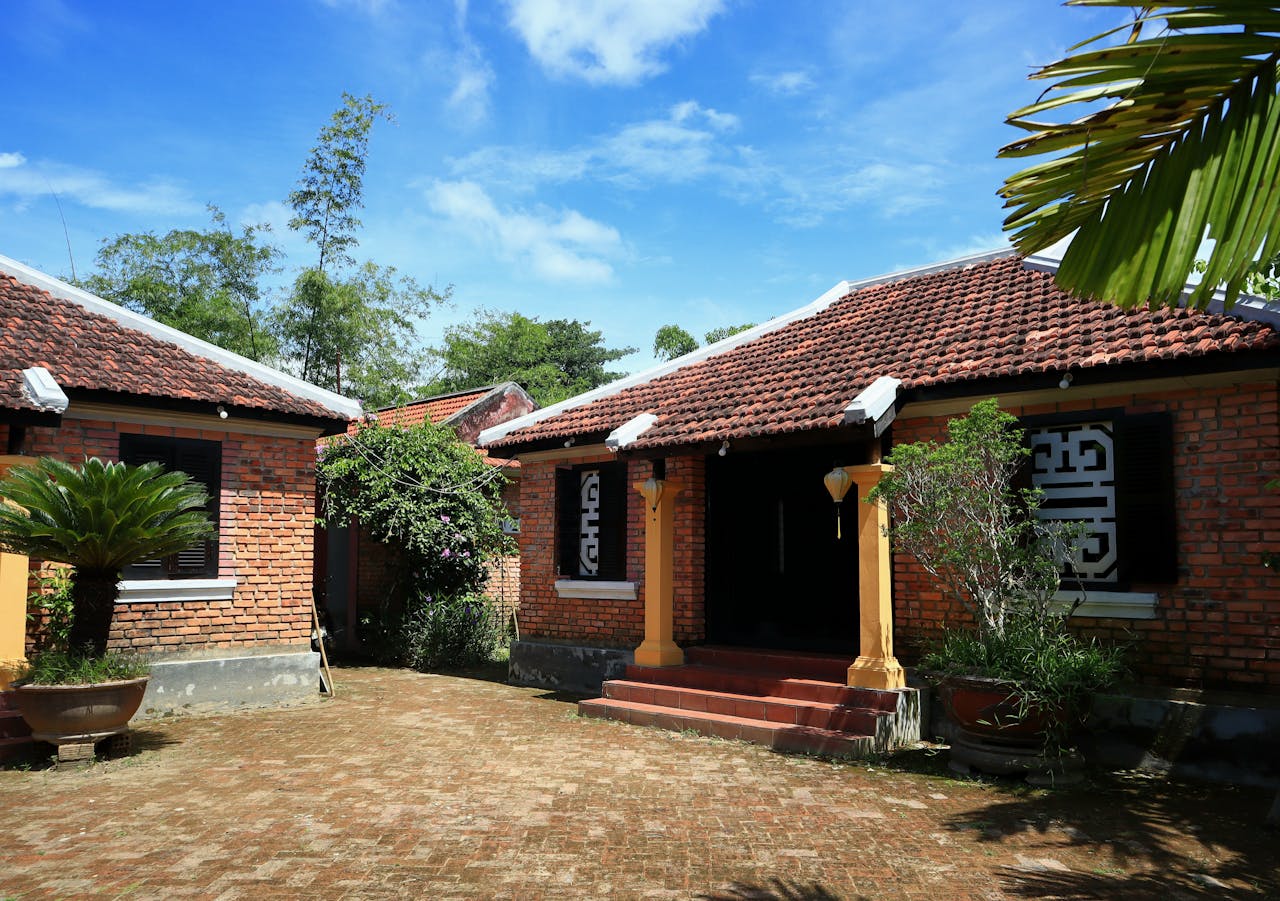 Beautiful traditional brick house with lush greenery under a bright blue sky.