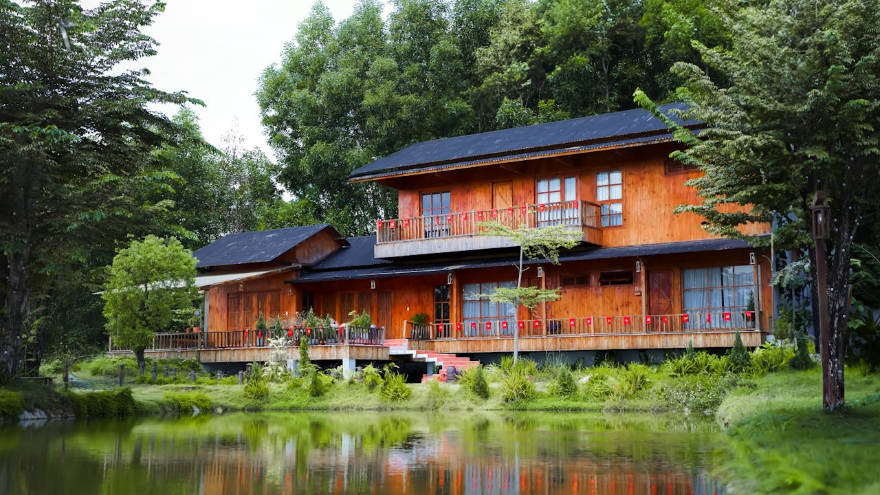 A picturesque wooden house surrounded by lush greenery reflected in a serene lake, evoking tranquility and natural beauty.