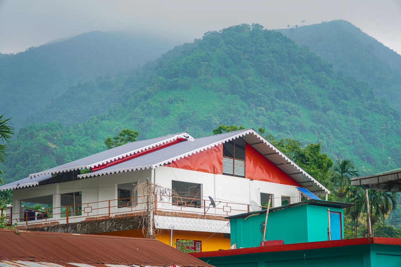 Colorful house nestled against misty green hills, showcasing natural serenity and vibrant architecture.